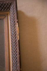 Antique painting's carved dark brown frame edge revealing chipping and exposed wood.