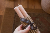 Branded ribbon and corrugated sleeve on a pair of blush beeswax taper candles.