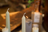 The faceted tips and wicks of celadon green square beeswax taper candles.