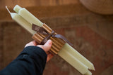 A pair of celadon green square taper beeswax candles in their paper sleeve and ribbon packaging.