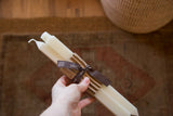 Hand holding cream square beeswax taper candles with 100% pure beeswax ribbon.