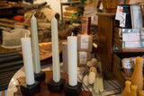 Cream column and light green taper beeswax candles on dark square holders.