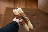 Cream column beeswax taper candles, bundled with paper and brown ribbon.