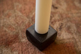 Detail of matte black cast iron candle holder with white taper candle.