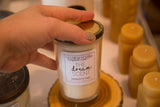 Hand holding cream 'DREAM' soy candle in vintage jelly jar with worn zinc lid.