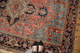 Vintage Heriz rug close-up showcasing rectilinear pattern and worn texture in blush, sea foam green, and indigo.