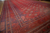 Brick red field with repeating gul motifs and intricate indigo blue Bokhara border.