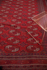 Brick red gul patterns and intricate indigo geometric border with abrashes on vintage Bokhara rug.