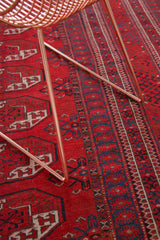 Vintage Afghan Bokhara rug showing repeating brick red gul design and an intricate indigo border.
