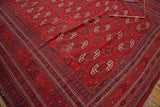 Vintage Afghan Bokhara rug corner showing intricate indigo geometric border and fringe.