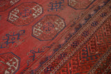 Vintage Afghan Bokhara rug detail, brick red gul motifs and intricate indigo border.