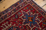 Vintage Karaja rug's corner with geometric medallion and curvilinear details in cherry red, navy, and teal.