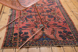 Tattered edge of a vintage Lilihan rug, displaying cranberry field and floral vinery.
