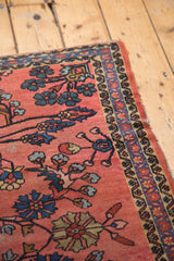 Vintage Lilihan rug corner detail, showing faded cranberry field, blue vinery, and tattered edge.