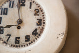 Aged folk art clock face with crackled cream paint, dark numbers, and rusty hands.