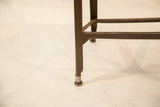 Dark metal leg and silver foot of a vintage Toledo chair, showing patina.