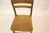 Angled view of the vintage Toledo kid's chair's worn wooden seat and dark metal frame.