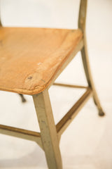 Worn wood seat of vintage Toledo kid's chair, showing chips and light green metal.