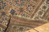 Antique Belouch runner end showing geometric patterns, worn pile, tattered fringe, and striped foundation.