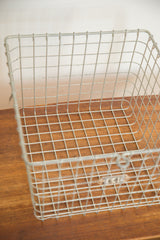 Worn numbered metal tag on the front of a mid century wire basket.