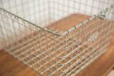 Detail of the industrial wire basket's gray grid and corner with a visible number tag.