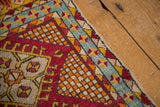 Vintage Yastic rug corner with teal pinwheel border, orange checkered field, and cherry red motifs.