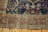 Tattered end and distressed border of an antique Farahan Sarouk rug, terra cotta and indigo.