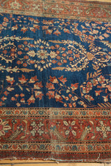 Antique Farahan Sarouk rug: indigo floral field, rich terra cotta border, and visible end wear.