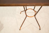 Weathered orange reclaimed metal base of the side table with circular design.