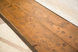 Reclaimed wood tabletop detail: warm brown planks with knots, next to dark industrial metal.