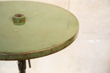 Distressed light green round industrial bistro table edge with chipped paint.