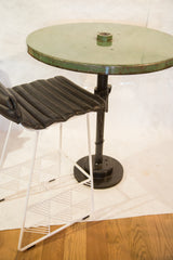 White geometric chair base and dark industrial table base on a white mat, wood floor.