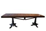 Reclaimed wood buffet table with a long plank top on two ornate vintage iron bases.