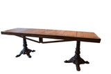 Angled view of a long reclaimed wood buffet table with two ornate pedestal bases.