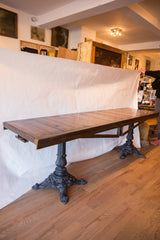 Long reclaimed wood buffet table with a plank top and two ornate vintage iron bases.