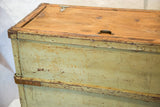 Distressed light green paint and natural wood lid of the vintage industrial cart.