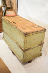 Distressed light green paint and brown metal banding on a vintage factory cart.