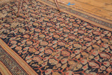 Vintage Hamadan rug's terra cotta boteh, saffron lattice vinery, navy field, and tattered end.