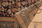 Vintage Hamadan rug edge: navy and terra cotta border, tattered fringe, visible foundation.