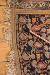 Tattered fringe and navy, terra cotta boteh paisley pattern on vintage Hamadan rug corner.
