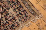 Corner of vintage Hamadan rug showing tattered fringe, exposed foundation, and worn border.