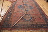Distressed fringe and muted palmette motifs in blush, bronze, and navy on a Hamadan rug end.