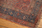 Antique Hamadan rug corner, distressed blush field, blue geometric border, tattered fringe.