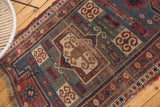 Worn red and teal geometric border with fringe on a circa 1900 Fachralo Kazak rug.