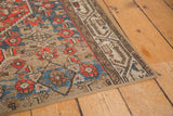 Corner of a vintage Hamadan rug fragment, distressed Mir Serbend border, tangerine, blue, and beige fabric binding.
