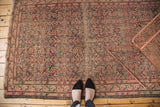 Antique Malayer rug's lower border showing distressed Herati pattern in blush and navy hues.