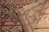 Antique Malayer rug corner showing distressed Herati pattern, tattered fringe, and woven foundation.
