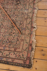 Distressed corner detail of an antique Malayer rug, intricate Herati patterns, tattered fringe.