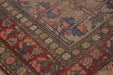 Worn patina reveals geometric leaf patterns and vibrant multi-color borders on a vintage rug.