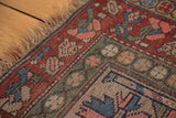 Natural camel hair fringe and geometric leaf motifs in blush, sky blue, brick red, and moss green border.